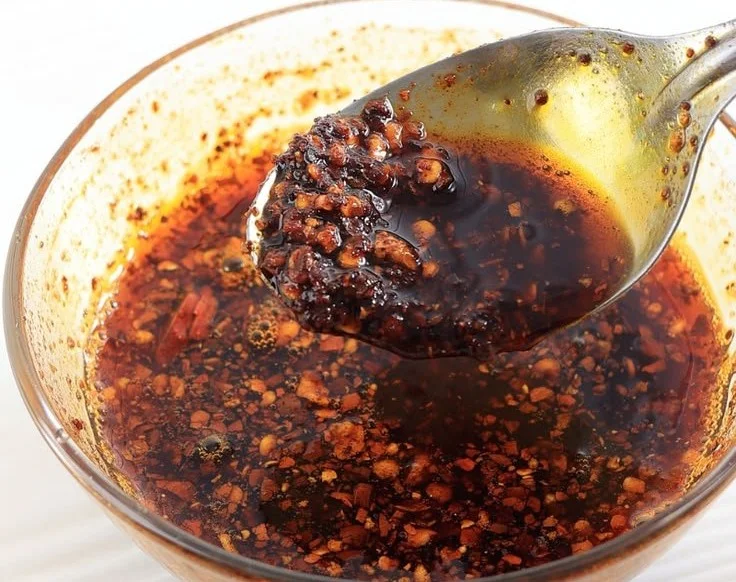 Homemade chili oil drizzled over a vibrant dish, showcasing its spicy flavor.