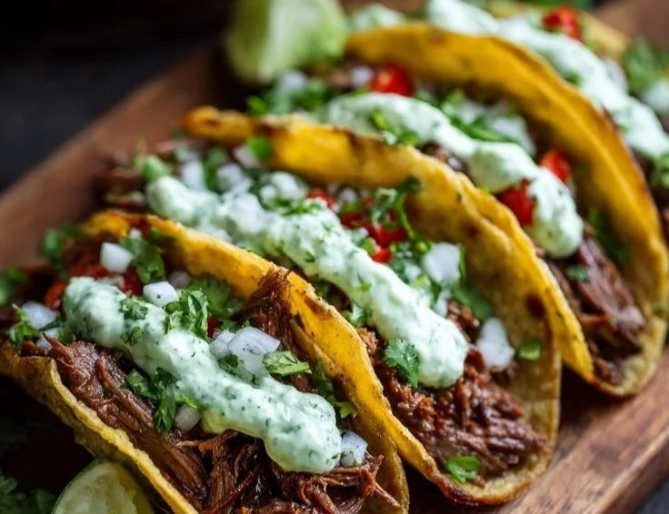 Crockpot beef skirt tacos with cilantro lime garlic sauce in a serving bowl.