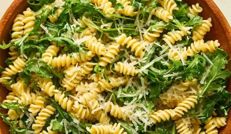 Fresh Lemon Arugula Pasta Salad in a bowl with herbs and lemon slices