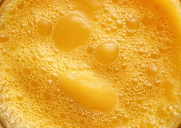 Fresh mango juice in a glass with mango slices and ice cubes