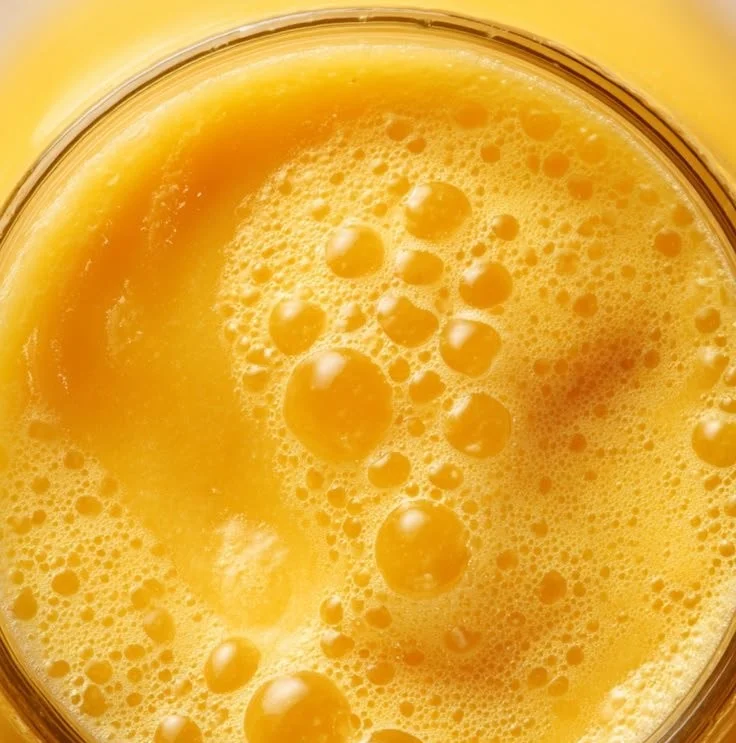 Glass of world's best mango juice with fresh mangoes on a wooden table