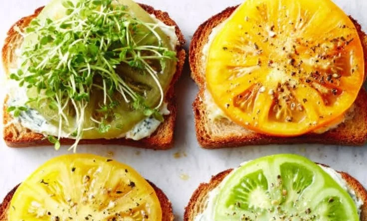 Heirloom tomato tartines topped with fresh herbs and creamy cheese.
