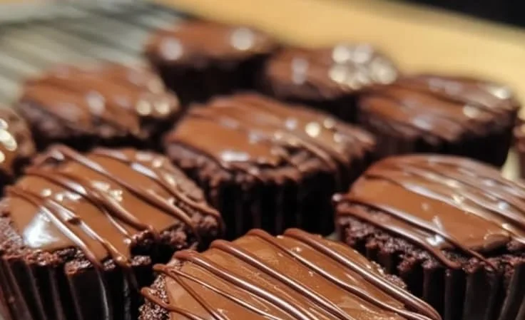 Decadent fudgy brownie bites drizzled with chocolate on a decorative plate.