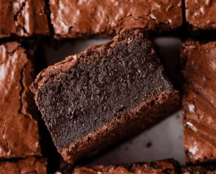 Delicious fudgy brownies topped with chocolate drizzle on a white plate.