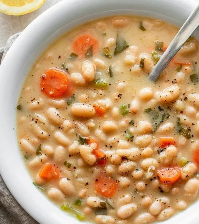 Bowl of Greek white bean soup with garlic and lemon garnish