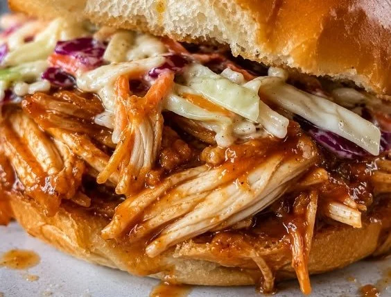 Slow cooker hot honey chicken sandwiches served on a plate with garnishes.