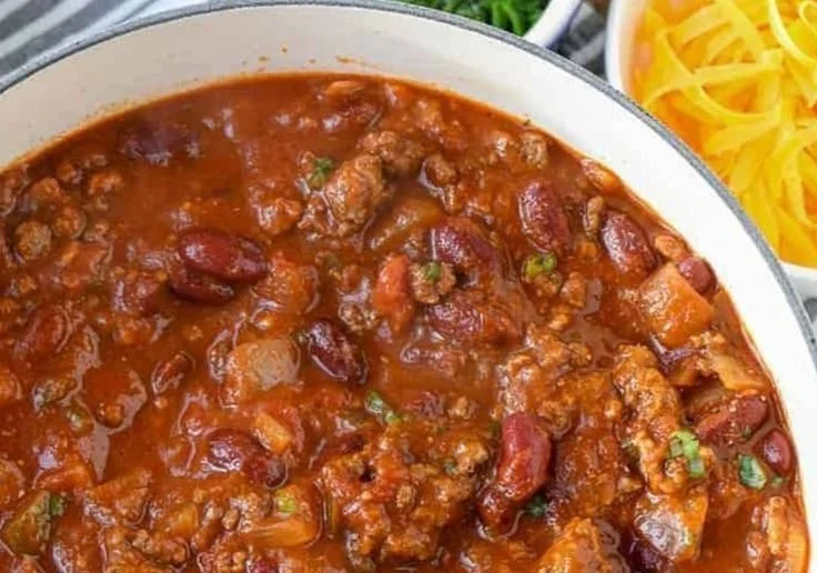 Bowl of flavorful chili soup garnished with fresh herbs, perfect for winter meals.