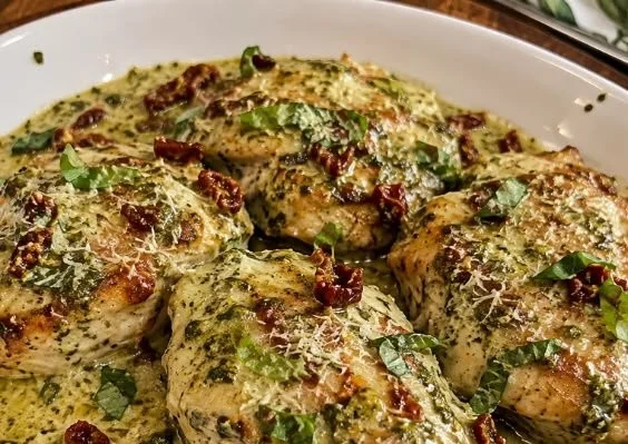 Creamy pesto chicken dish garnished with fresh herbs