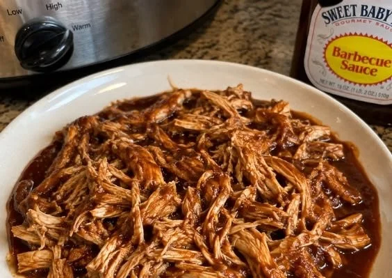 Sweet Baby Ray’s Crockpot Chicken served in a bowl with sauce and herbs